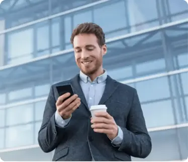 A businessman holding a cup of coffee and looking at his phone